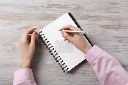 Téléchargez les photos : Femme écrivant dans un cahier à une table en bois blanc, vue de dessus - en image libre de droit