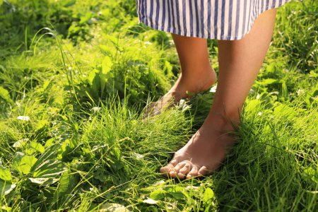 Foto de Mujer caminando descalza sobre hierba verde, primer plano. Espacio para texto - Imagen libre de derechos