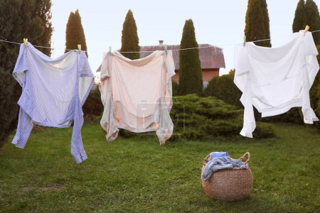 Photo for Clean clothes drying near wicker bag in backyard - Royalty Free Image