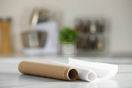 Téléchargez les photos : Rouleaux de papier cuisson sur table en marbre blanc sur fond flou à l'intérieur. Espace pour le texte - en image libre de droit