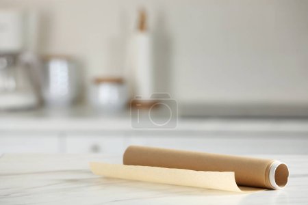 Téléchargez les photos : Rouleau de papier cuisson sur table en marbre blanc sur fond flou à l'intérieur. Espace pour le texte - en image libre de droit