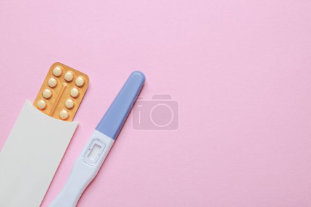 Téléchargez les photos : Pilules contraceptives et test de grossesse sur fond rose, vue de dessus. Espace pour le texte - en image libre de droit