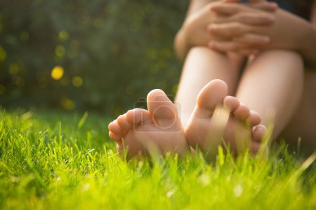 Foto de Adolescente sentada descalza sobre hierba verde al aire libre, de cerca. Espacio para texto - Imagen libre de derechos