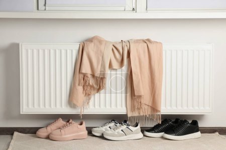 Téléchargez les photos : Chauffage radiateur avec écharpe et chaussures près de la fenêtre dans la chambre - en image libre de droit