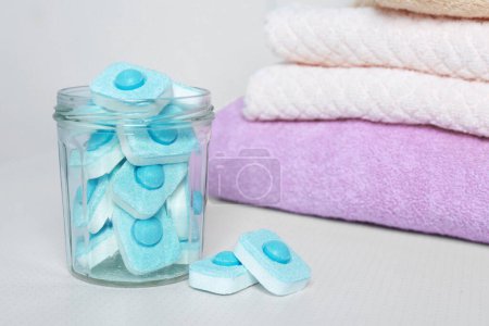 Photo for Jar with water softener tablets near stacked towels on white table - Royalty Free Image