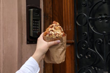 Téléchargez les photos : Femme tenant un délicieux croissant près de la porte, gros plan - en image libre de droit