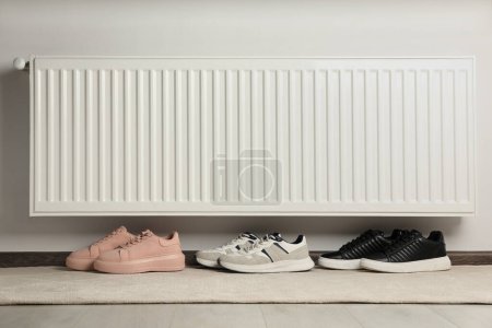 Téléchargez les photos : Chaussures près de radiateur de chauffage blanc dans la chambre - en image libre de droit