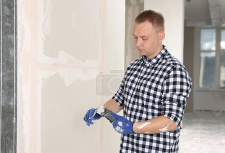 Foto de Trabajador con cuchillos de masilla y yeso cerca de la pared interior. Renovación del hogar - Imagen libre de derechos