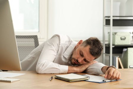 Foto de Hombre cansado durmiendo en el lugar de trabajo en la oficina - Imagen libre de derechos