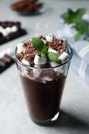 Téléchargez les photos : Verre de délicieux chocolat chaud avec guimauves et menthe fraîche sur table gris clair - en image libre de droit