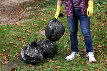Foto de Hombre sosteniendo bolsas de plástico con basura en el parque, primer plano. - Imagen libre de derechos