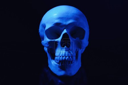 Téléchargez les photos : Crâne humain bleu avec des dents sur fond noir - en image libre de droit
