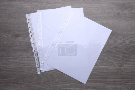 Foto de Bolsillos perforados con hojas de papel sobre mesa de madera, plano - Imagen libre de derechos