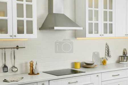 Elegantes Kücheninterieur mit moderner Dunstabzugshaube über Kochfeld und stilvollen Möbeln