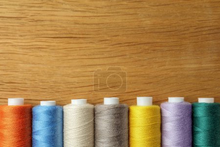 Foto de Muchos hilos de costura de colores en la mesa de madera, la puesta plana. Espacio para texto - Imagen libre de derechos
