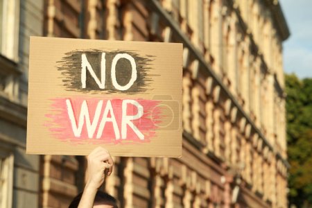Foto de Mujer sosteniendo cartel con palabras No War al aire libre. Espacio para texto - Imagen libre de derechos