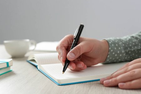 Foto de Mujer escribiendo en cuaderno en la mesa de madera en la oficina, primer plano - Imagen libre de derechos