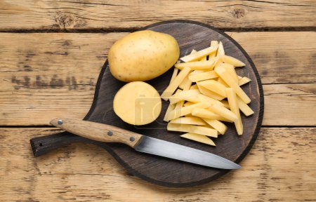 Téléchargez les photos : Pommes de terre entières et coupées au couteau sur une table en bois, vue sur le dessus. Cuisiner de délicieuses frites - en image libre de droit