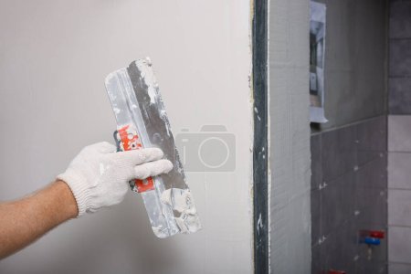 Photo for Worker plastering wall with putty knife indoors, closeup - Royalty Free Image