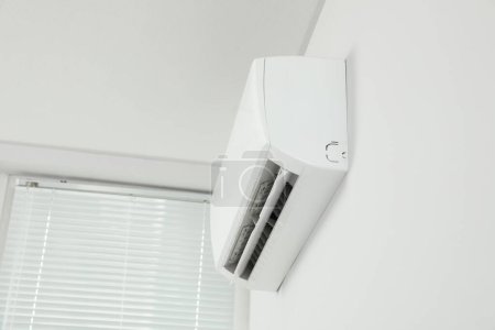 Foto de Acondicionador de aire moderno en la pared blanca en interiores, vista de ángulo bajo - Imagen libre de derechos