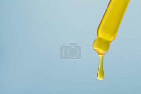 Foto de Goteando suero amarillo de la pipeta sobre fondo gris, primer plano. Espacio para texto - Imagen libre de derechos