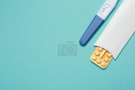 Téléchargez les photos : Pilules contraceptives et test de grossesse sur fond bleu clair, vue de dessus. Espace pour le texte - en image libre de droit