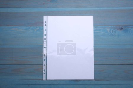 Foto de Bolsillo perforado con hoja de papel sobre mesa de madera azul claro, vista superior - Imagen libre de derechos