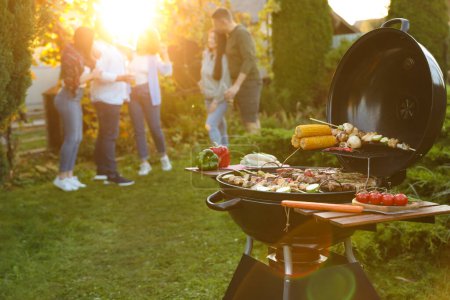 Groupe d'amis faisant la fête à l'extérieur. Focus sur barbecue grill avec de la nourriture. Espace pour le texte