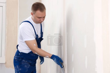 Photo for Man plastering wall with putty knife indoors. Home renovation - Royalty Free Image