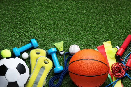 Photo for Set of different colorful sports equipment on green grass, flat lay. Space for text - Royalty Free Image