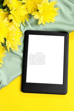 Téléchargez les photos : Lecteur de livres électroniques moderne et fleurs sur fond jaune, pose plate - en image libre de droit