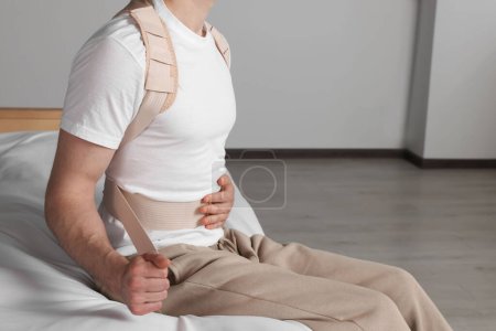Photo for Closeup view of man with orthopedic corset sitting in room - Royalty Free Image
