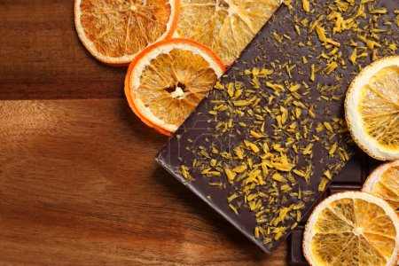 Chocolate bars with freeze dried orange on wooden table, top view. Space for text
