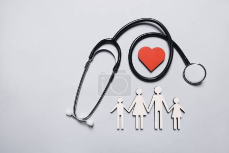 Figures of family near stethoscope and heart on white background, flat lay. Insurance concept
