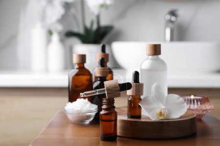 Ätherische Öle, Orchideenblume und Meersalz auf Holztisch im Badezimmer