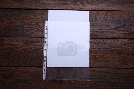 Foto de Bolsillo perforado con hoja de papel sobre mesa de madera, vista superior - Imagen libre de derechos