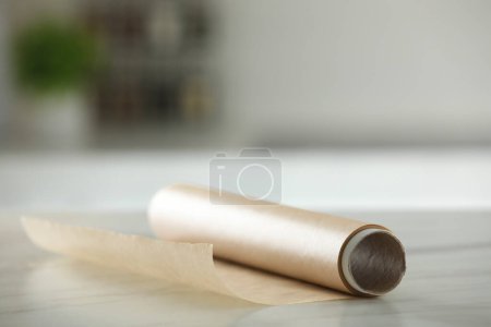 Téléchargez les photos : Rouleau de papier cuisson sur table en marbre blanc sur fond flou à l'intérieur - en image libre de droit
