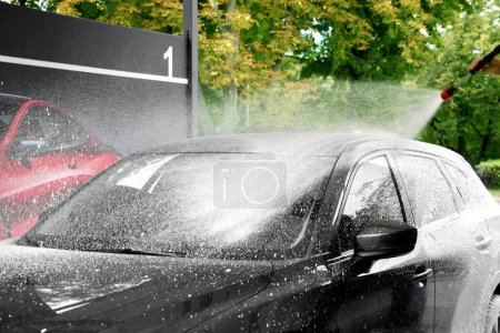 Téléchargez les photos : Homme lavage automatique avec jet d'eau haute pression au lavage de voiture extérieure, gros plan - en image libre de droit