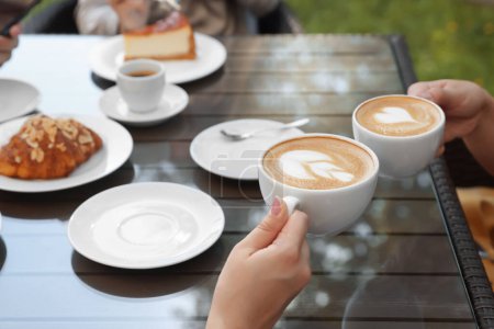 Foto de Amigos tomando café en la mesa de madera en la cafetería al aire libre, primer plano - Imagen libre de derechos