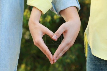 Téléchargez les photos : Couple faisant coeur avec les mains à l'extérieur le jour ensoleillé, gros plan - en image libre de droit