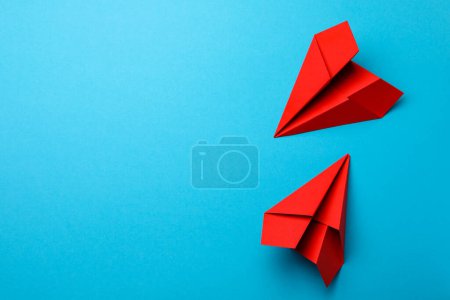 Téléchargez les photos : Avions en papier rouge faits à la main sur fond bleu clair, pose plate. Espace pour le texte - en image libre de droit