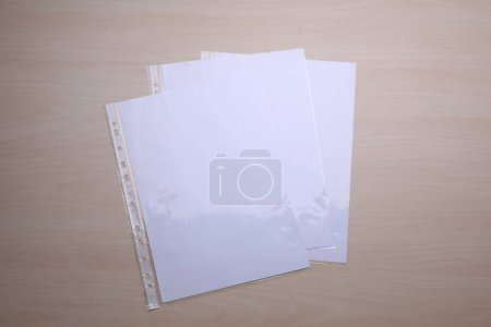Foto de Bolsillos perforados con hojas de papel sobre mesa de madera, plano - Imagen libre de derechos