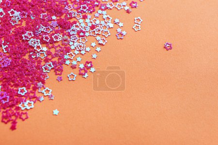 Photo for Shiny bright star shaped glitter on pale coral background. Space for text - Royalty Free Image
