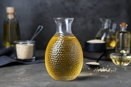 Photo for Fresh sesame oil in glass bottle on grey table - Royalty Free Image