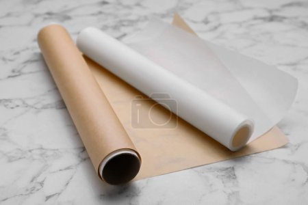 Rollos de papel de hornear sobre mesa de mármol blanco