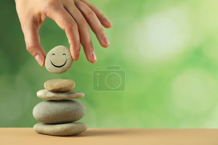 Foto de Mujer poniendo piedra con la cara feliz dibujado en la pila contra el fondo borroso, primer plano y espacio para el texto. Concepto zen - Imagen libre de derechos