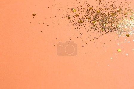 Photo for Shiny bright golden glitter on pale coral background. Space for text - Royalty Free Image