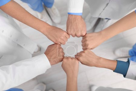 Photo for Team of medical doctors putting hands together indoors, above view - Royalty Free Image
