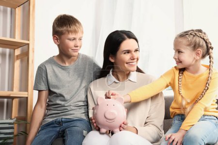 Glückliche Familie steckt zu Hause Münze in Sparschwein