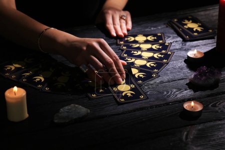 Téléchargez les photos : Apaisant prédisant l'avenir avec des cartes de tarot à table dans l'obscurité, gros plan - en image libre de droit